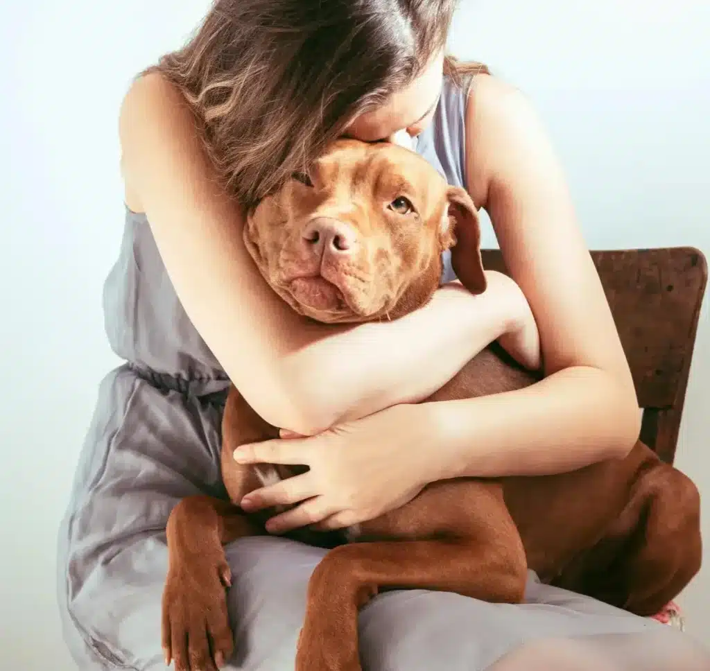 Hondenconsult bij Dog Dimension: vrouw omhelst hond op stoel met probleemgedrag.